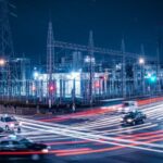AIデータセンター建設ラッシュの影響で米東部の電気料金が76%上昇。現代の都市環境を背景に、エネルギー需要の抽象的な表現を描写。