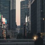 スペースXのビットコイン保有額は約2,200億円で、世界7位の規模。都市の中でデジタル通貨を象徴するスマートフォンを持つ人のシルエットを描写。