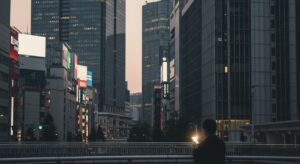スペースXのビットコイン保有額は約2,200億円で、世界7位の規模。都市の中でデジタル通貨を象徴するスマートフォンを持つ人のシルエットを描写。